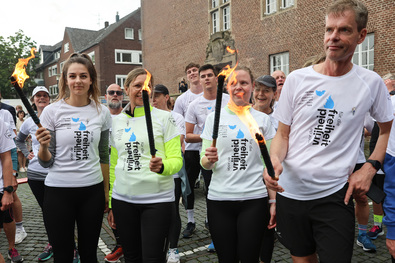 Läuferinnen und Läufer mit brennenden Fackeln auf dem Rathausvorplatz in Emmerich (Foto: Sabine Stein).