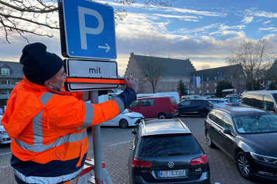 Mitarbeiter der Kommunalbetriebe überklebt das Zusatzschild "Mit Parkschein" auf dem Geistmarkt.