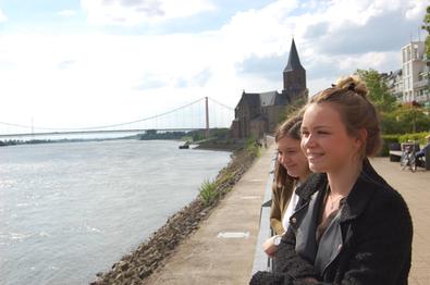 Zwei junge Frauen an der Rheinpromenade - im Hintergrund die Rheinbrücke